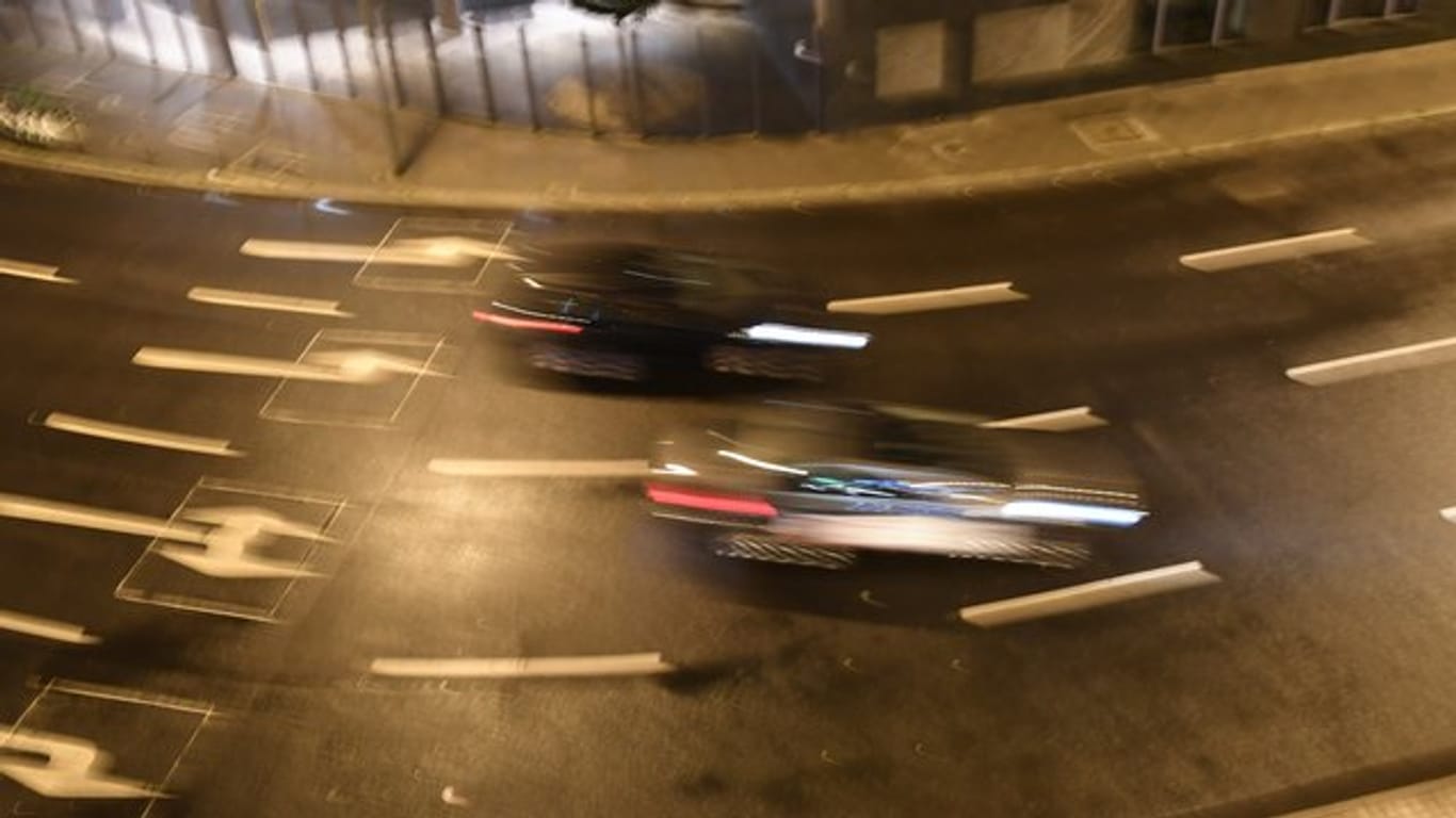 Autos am Abend auf einer Straße mit Straßenmarkierungen und Abbiegepfeilen.