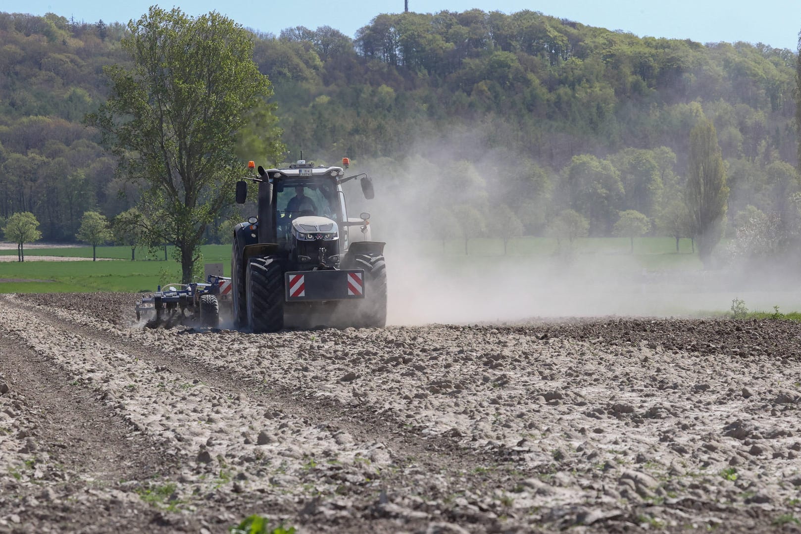 Dürre: Landwirt eggt mit einem Traktor ein staubtrockenes Feld.