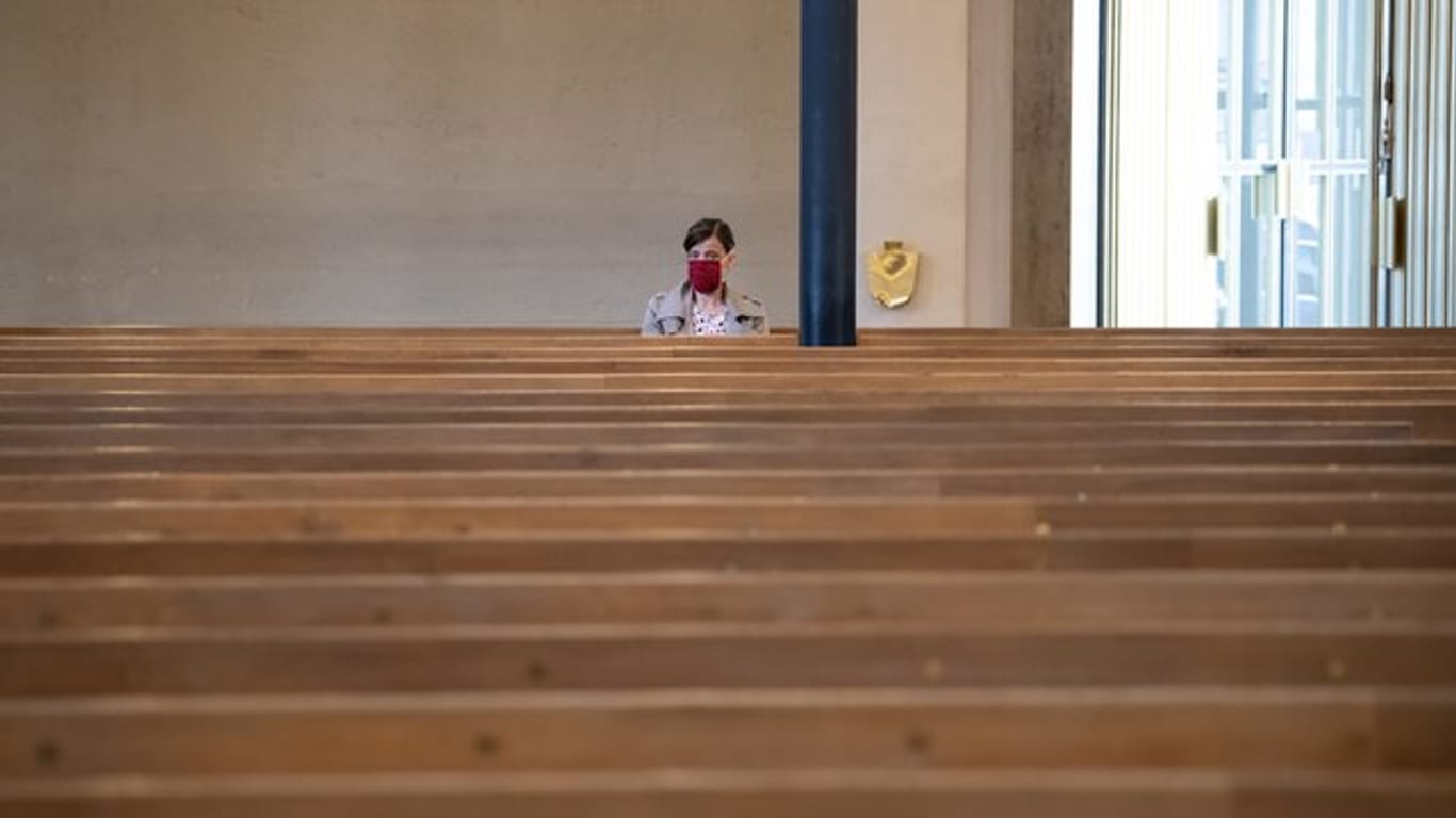 Eine Frau sitzt mit Mundschutz in der ansonsten fast menschenleeren St.