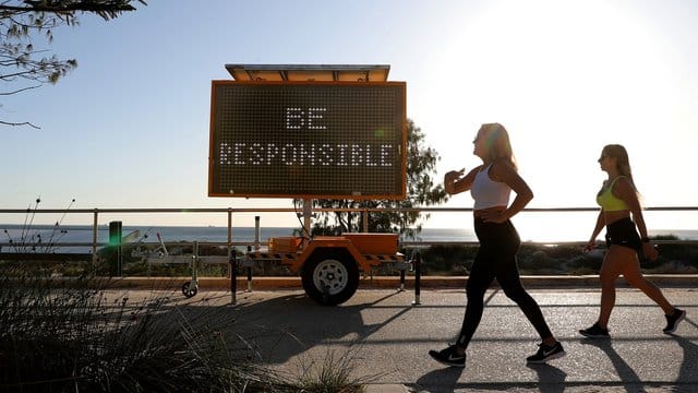 Walking in Corona-Zeiten: Frauen gehen in Perth an einer digitalen Anzeige mit der Aufschrift "Be Responsible" (Seid verantwortungsvoll) vorbei.