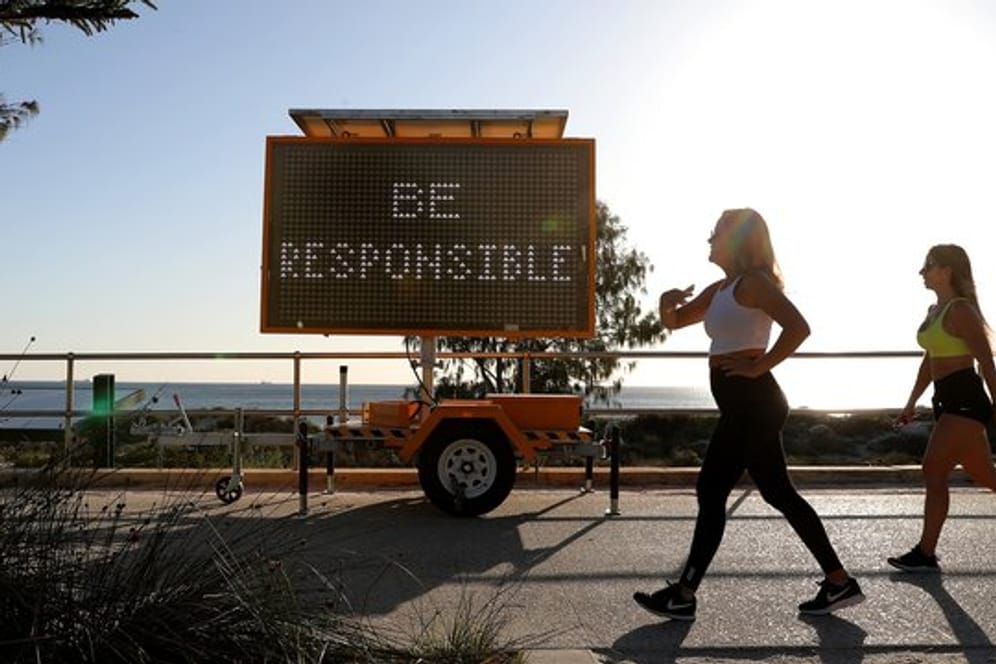 Walking in Corona-Zeiten: Frauen gehen in Perth an einer digitalen Anzeige mit der Aufschrift "Be Responsible" (Seid verantwortungsvoll) vorbei.