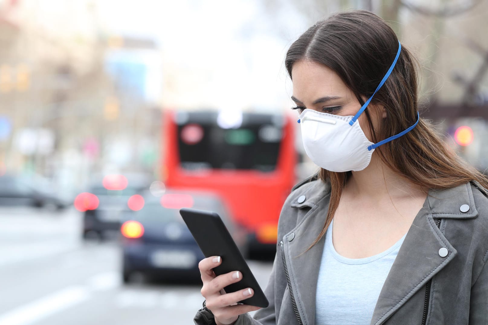 Eine Frau mit Smartphone und Maske: Derzeit wird nach einem Konzept für eine Corona-Warn-App gesucht.