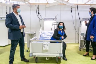 Im Behandlungszentrum auf der Messe Berlin: Gesundheitssenatorin Dilek Kalayci (SPD) sitzt auf einem der Krankenhausbetten, links neben ihr steht SPD-Fraktionschef Raed Saleh.