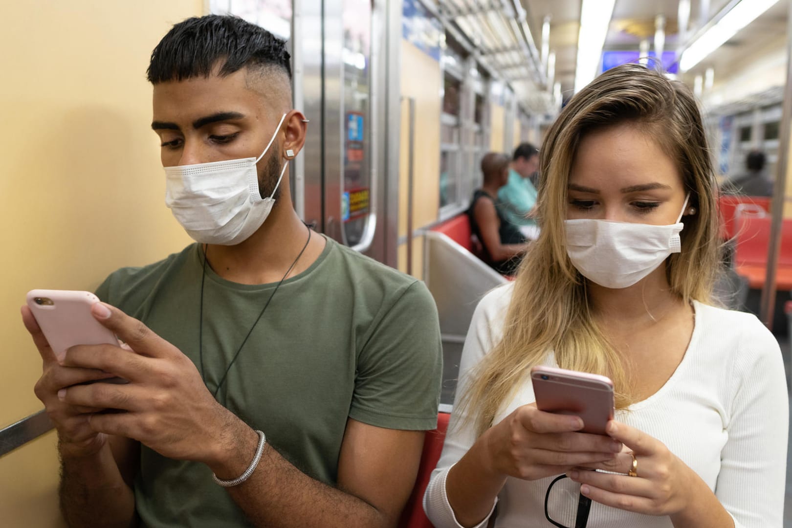 Menschen mit Maske und Smartphone (Symbolbild): Derzeit für über ein Konzept für eine Corona-Warn-App diskutiert.