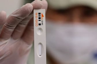 Ein Mitarbeiter von Boditech Med hält ein Teströhrchen für einen Covid-19-Antikörpertest in der Hand.