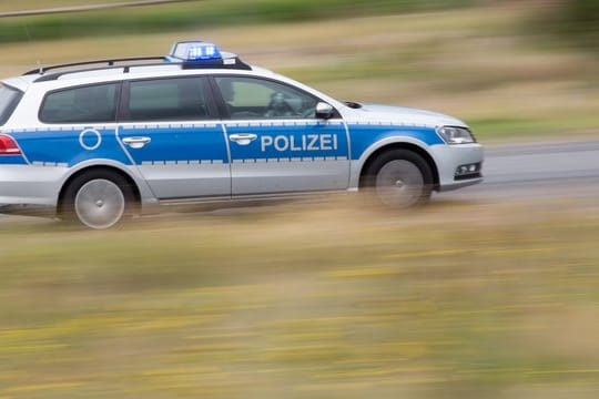 Ein Streifenwagen fährt mit Blaulicht über eine Straße