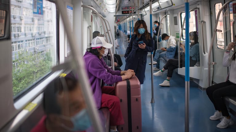 Wuhan in China: Passagiere sitzen in Einhaltung des Mindestabstands und mit Mundschutz in einem Zugwaggon.