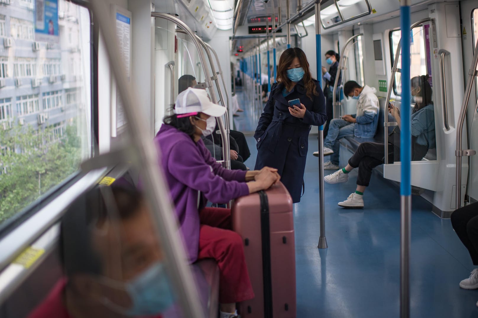 Wuhan in China: Passagiere sitzen in Einhaltung des Mindestabstands und mit Mundschutz in einem Zugwaggon.