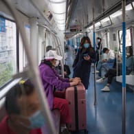 Wuhan in China: Passagiere sitzen in Einhaltung des Mindestabstands und mit Mundschutz in einem Zugwaggon.