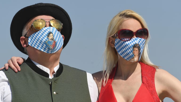 Der Geschäftsführer von Angermaier Trachten und seine Freundin Yvonne tragen blau-weiße Trachtenmasken: In Bayern drohten Maskenverweigerern saftige Bußgelder.
