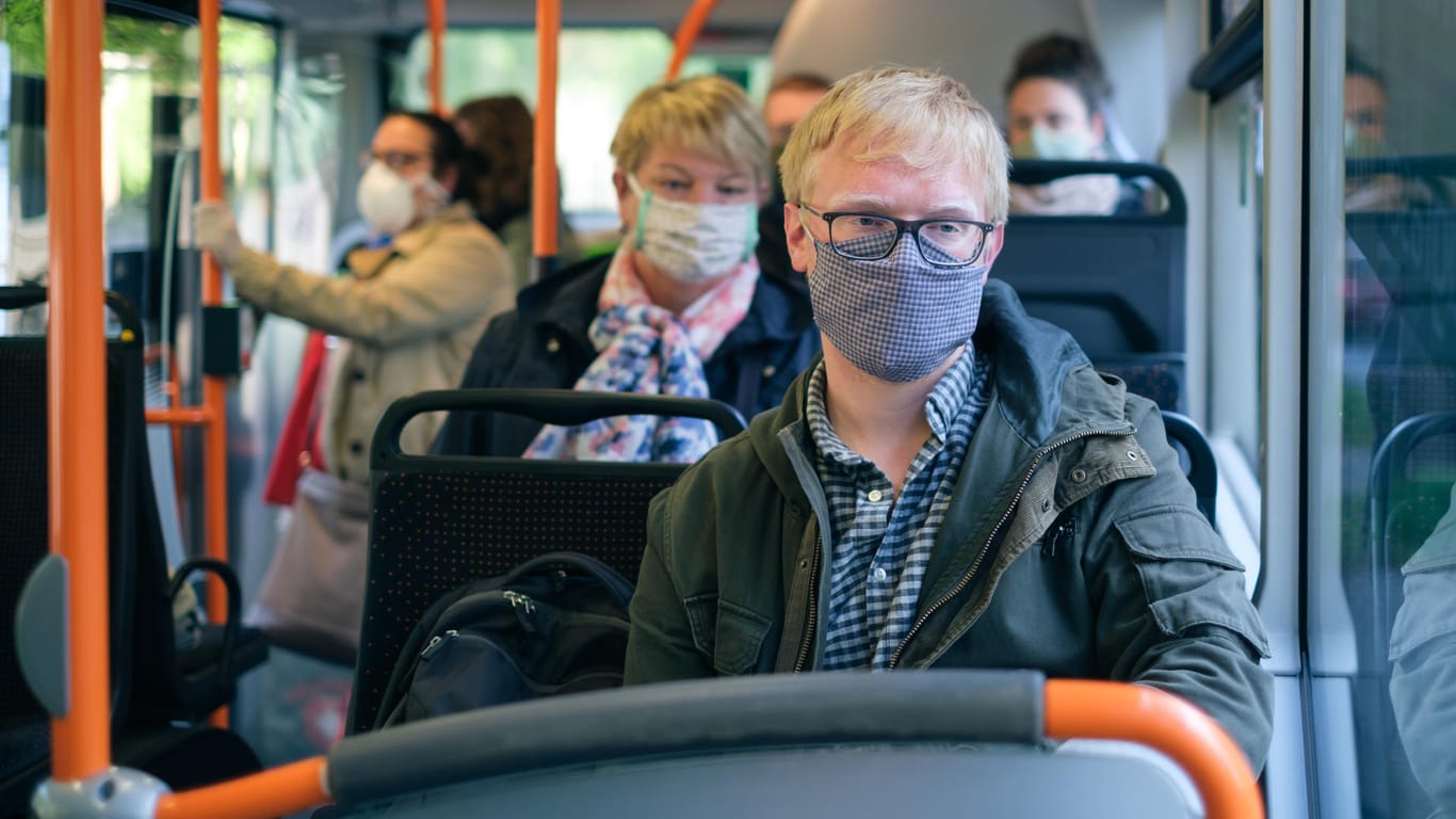 Menschen tragen Mundschutz in einem Bus: Weltweit gibt es nun drei Millionen Corona-Infizierte.