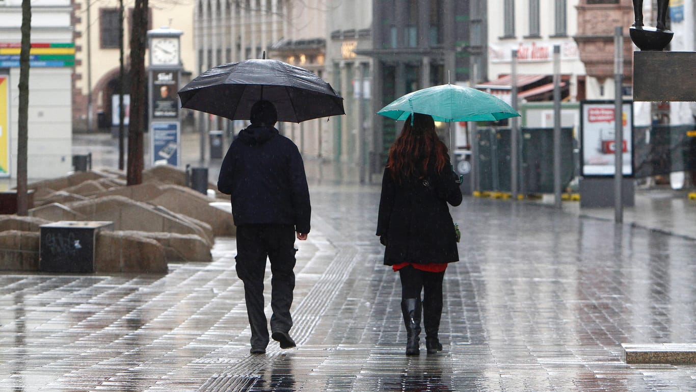 Ein Paar geht mit Regenschirmen durch eine sonst menschenleere Fußgängerzone: Mit Dauerregen ist nicht zu rechnen, doch die ganze Woche lang ziehen Schauer über Deutschland. (Archivbild)