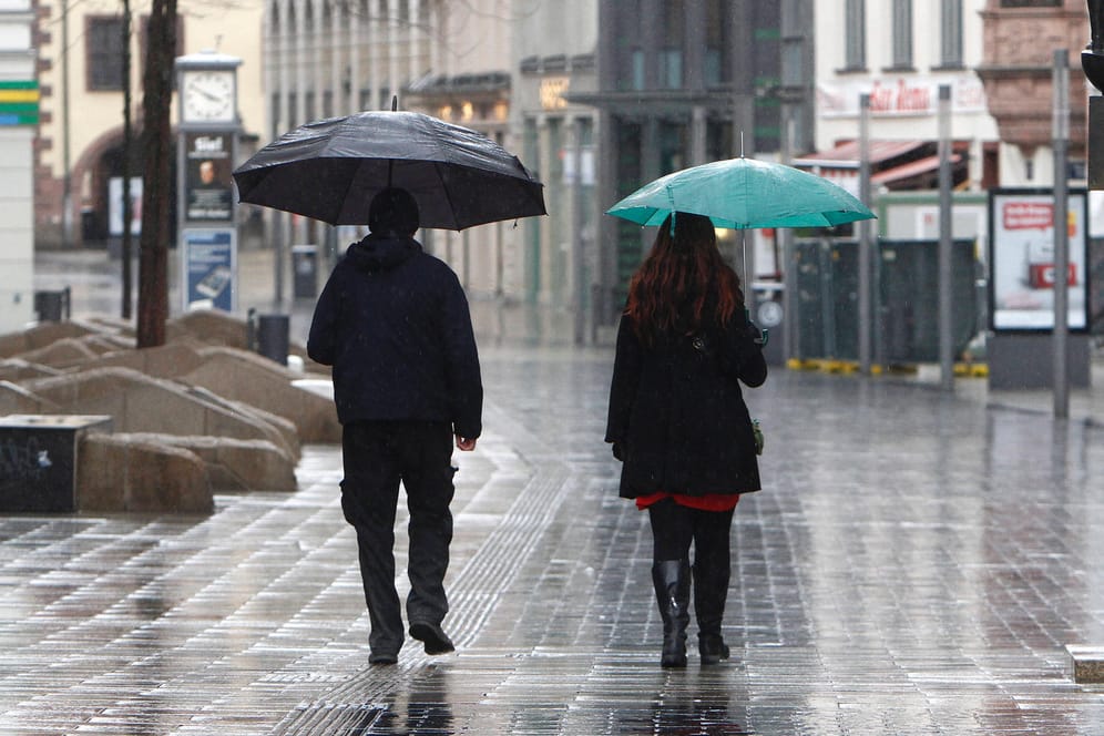 Ein Paar geht mit Regenschirmen durch eine sonst menschenleere Fußgängerzone: Mit Dauerregen ist nicht zu rechnen, doch die ganze Woche lang ziehen Schauer über Deutschland. (Archivbild)