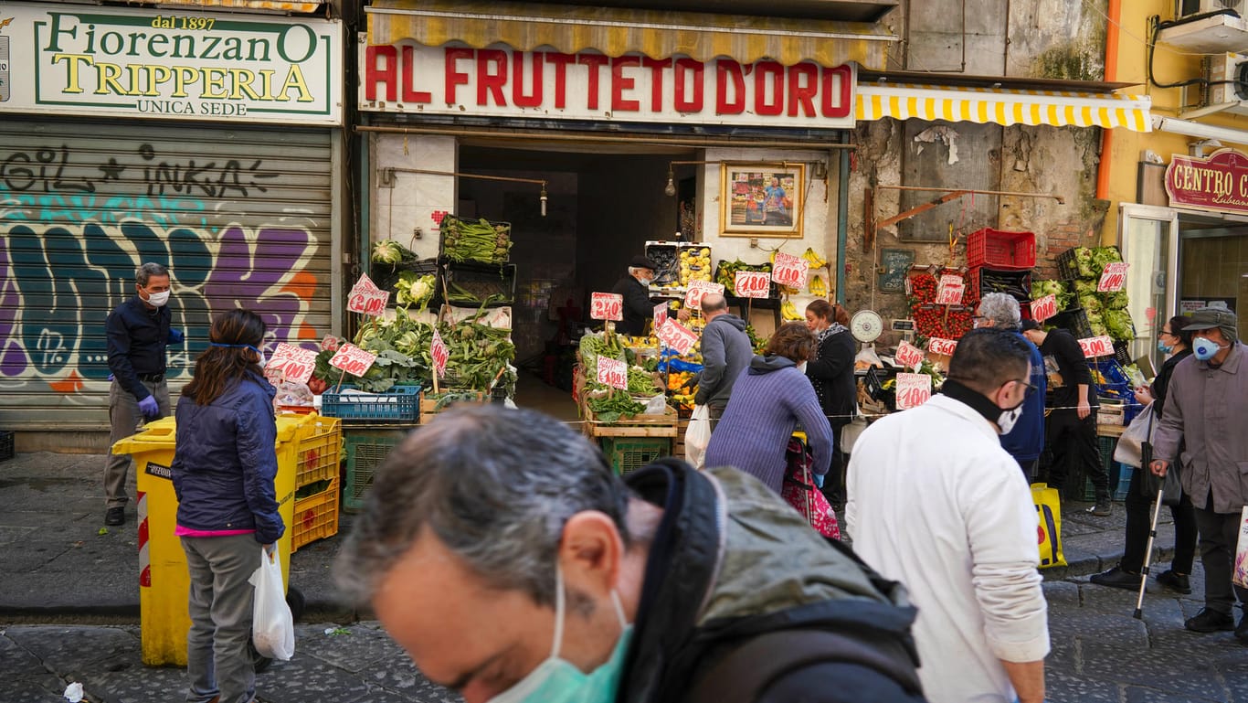 Kunden mit Mundschutz kaufen Obst und Gemüse bei einem kleinen Händler: Die meisten Geschäfte, zum Beispiel Modeläden, dürfen erst ab dem 18. Mai öffnen.
