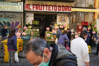 Kunden mit Mundschutz kaufen Obst und Gemüse bei einem kleinen Händler: Die meisten Geschäfte, zum Beispiel Modeläden, dürfen erst ab dem 18. Mai öffnen.