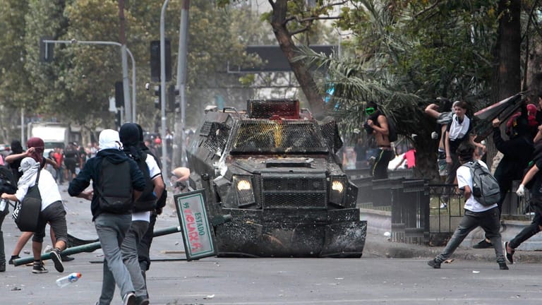 Demonstranten in Santiago de Chile attackieren Mitte März ein Polizeifahrzeug.