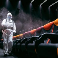 Kinos in der Krise: In einem Saal in Tallinn versprühen Mitarbeiter in Schutzanzügen Desinfektionsspray.