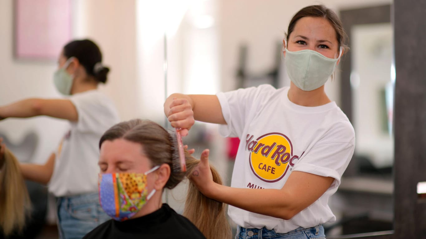Eine Friseurin mit Mundschutz kämmt einer Kundin die Haare (Symbolbild): In Berlin öffnen Friseure ab Anfang Mai wieder.