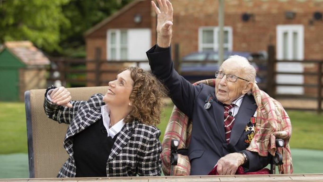 Hauptmann Tom Moore und seine Tochter Hannah winken, während eine Einheit der Royal Air Force über sein Haus fliegt.