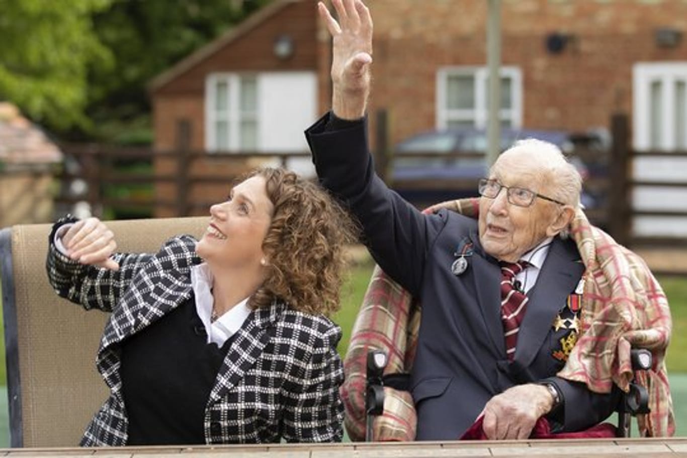 Hauptmann Tom Moore und seine Tochter Hannah winken, während eine Einheit der Royal Air Force über sein Haus fliegt.