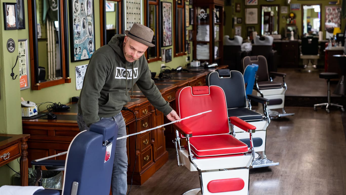 Ein Friseur misst die Abstände zwischen den Stühlen für die Kunden: Am Montag dürfen die Frisuere wieder öffnen (Symbolbild).