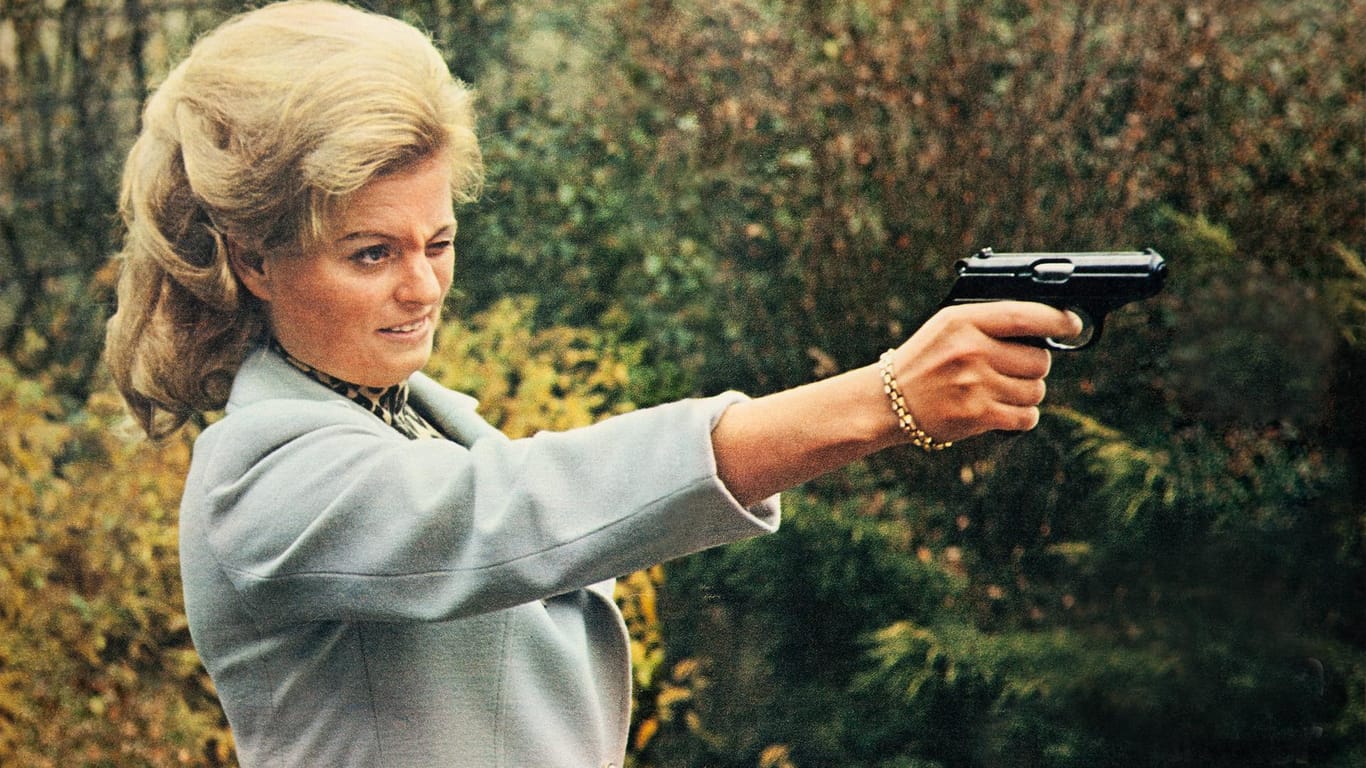 Hannelore Kohl zielt mit einer Pistole.