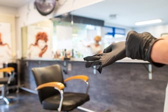 Eine Friseurin zieht Schutzhandschuhe an