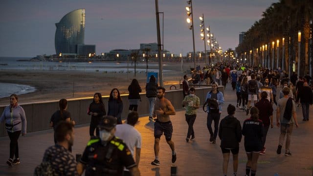 Menschen gehen bei Sonnenuntergang auf einer Strandpromenade spazieren und treiben Sport. Menschen gehen bei Sonnenuntergang auf einer Strandpromenade spazieren und treiben Sport.