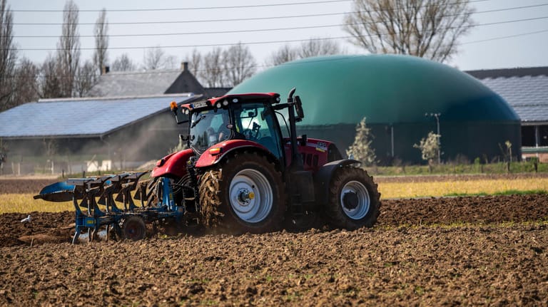 Trecker mit Pflug vor einer Biogasanlage: Neben Energiepflanzen werden in den Anlagen auch Gülle und Bioabfälle verwertet.