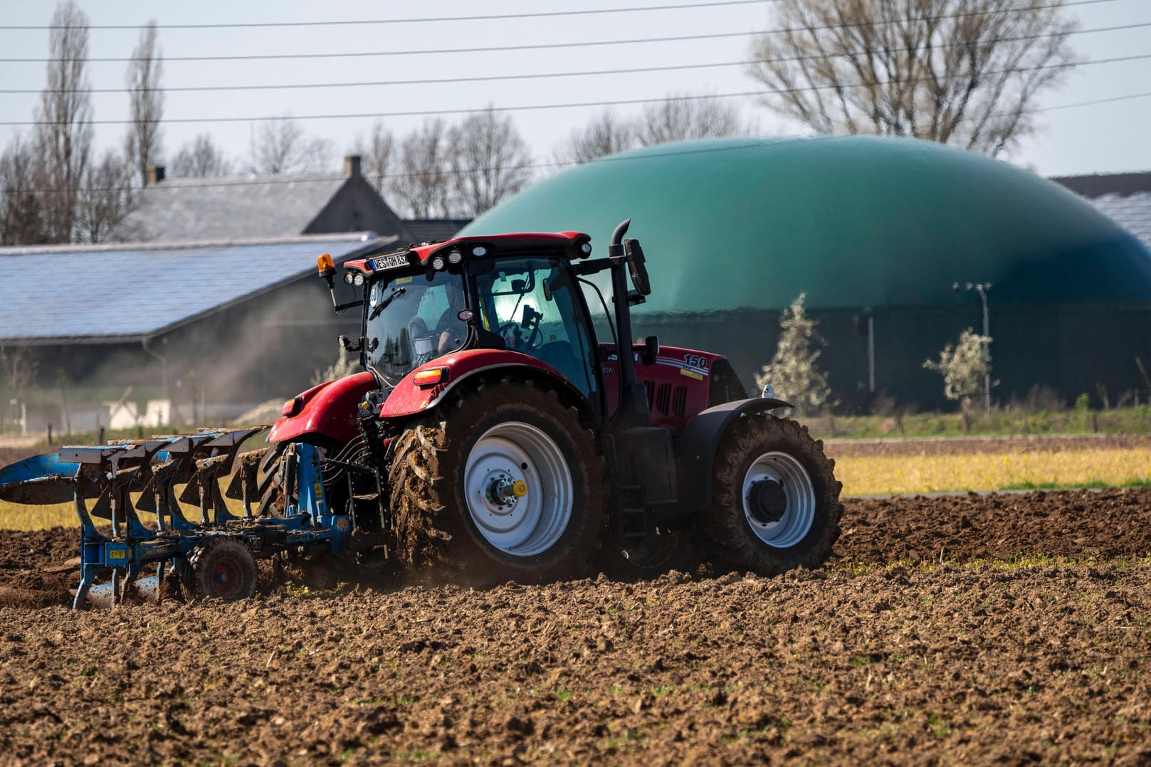 Trecker mit Pflug vor einer Biogasanlage: Neben Energiepflanzen werden in den Anlagen auch Gülle und Bioabfälle verwertet.