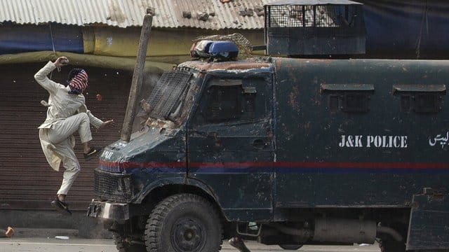 Ein maskierter kaschmirischer Demonstrant springt auf die Motorhaube eines gepanzerten Fahrzeugs der indischen Polizei während einer Demonstration in Srinagar. Ein maskierter kaschmirischer Demonstrant springt auf die Motorhaube eines gepanzerten Fahrzeugs der indischen Polizei während einer Demonstration in Srinagar.