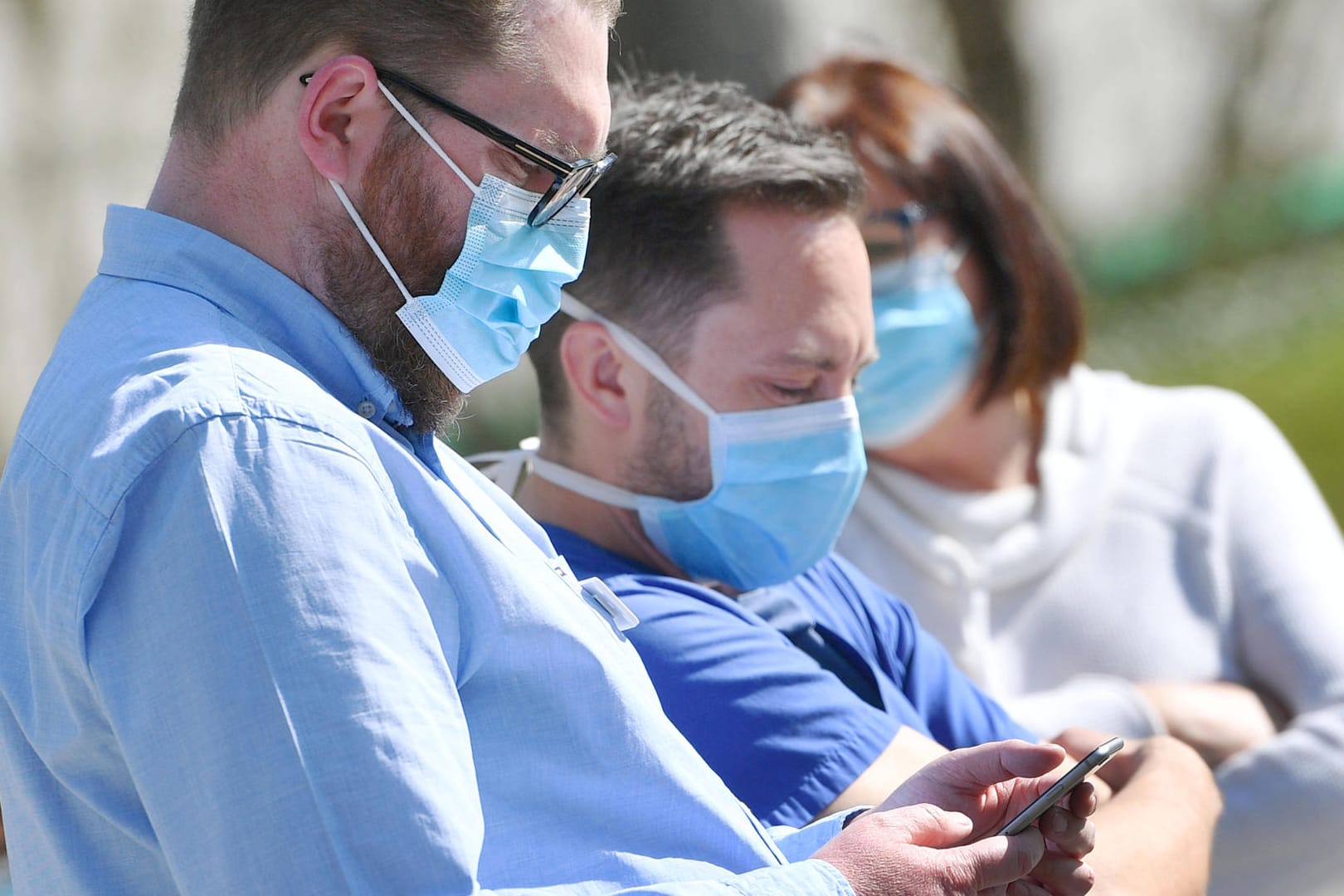 Menschen mit Maske und Smartphone (Symbolbild): Apple und Google arbeiten an einem Konzept für eine Corona-App.