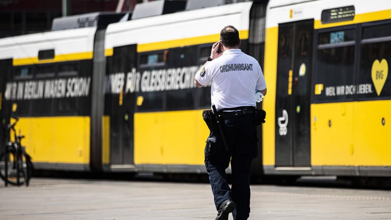Ein Beamter vom Ordnungsamt telefoniert vor einer ankommenden Tram in Berlin (Symbolbild): In Hellersdorf hat eine Tram ein Mädchen angefahren.