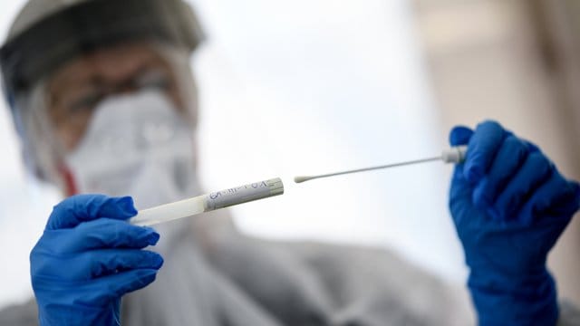 Eine Mitarbeiterin des Gesundheitsamts in Berlin-Mitte hält ein Abstrichstäbchen in einer ambulanten Test-Einrichtung in der Hand. Eine Mitarbeiterin des Gesundheitsamts in Berlin-Mitte hält ein Abstrichstäbchen in einer ambulanten Test-Einrichtung in der Hand.