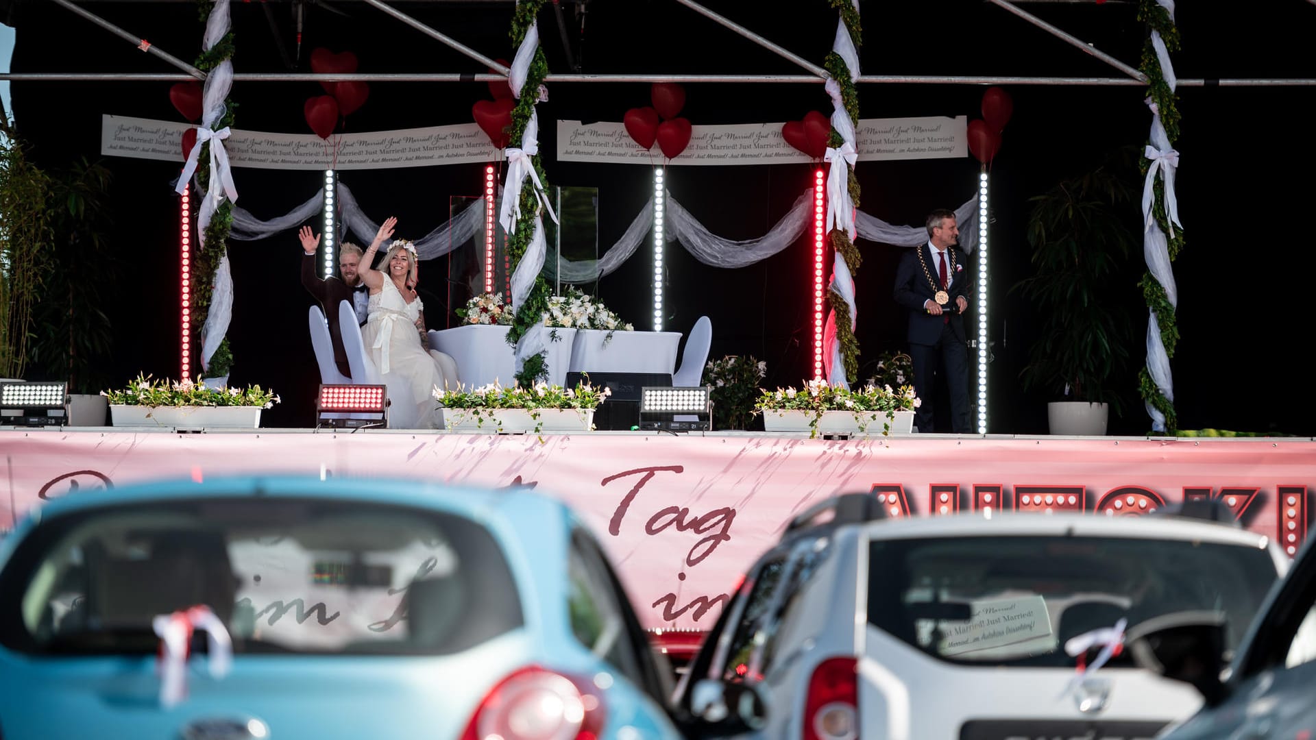 Das Brautpaar Janine und Philip Scholz winkt den Hochzeitsgästen zu: Aus 30 Autos verfolgten Angehörige die Hochzeit im Autokino. Das Brautpaar Janine und Philip Scholz winkt den Hochzeitsgästen zu: Aus 30 Autos verfolgten Angehörige die Hochzeit im Autokino.