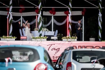 Das Brautpaar Janine und Philip Scholz winkt den Hochzeitsgästen zu: Aus 30 Autos verfolgten Angehörige die Hochzeit im Autokino.