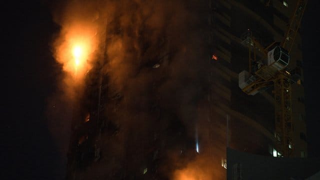 Ein Feuer brennt an der Seite des Hochhauses in Schardscha.