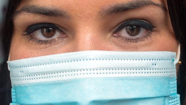 Eine Frau steht mit Mundschutz in einem Geschäft. Eine Frau steht mit Mundschutz in einem Geschäft.