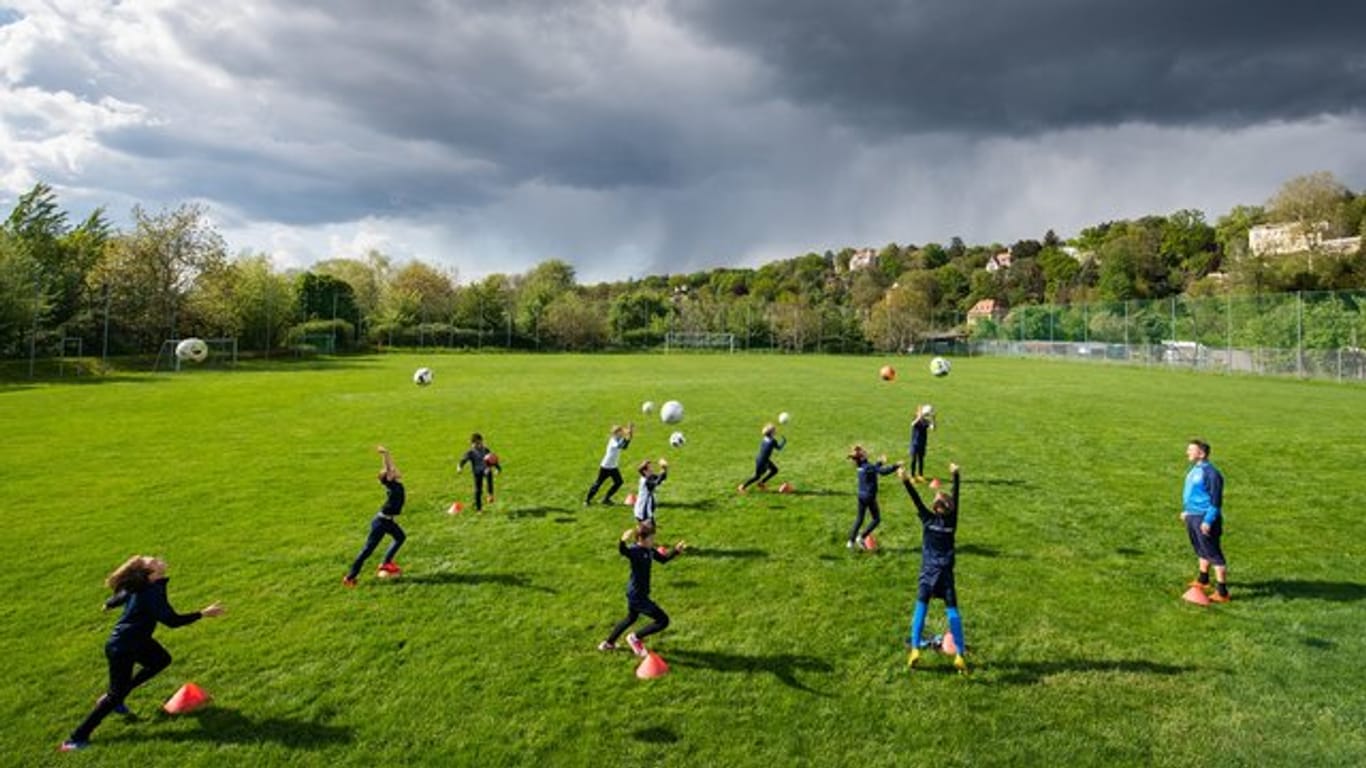 Fußballer trainieren auf einem Spielfeld in großen Abständen