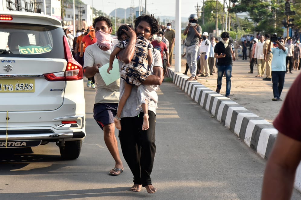 Vishakhapatnam in Indien: Ein Mann trägt ein Kind auf einer Straße, weitere Männer folgen, nach einem Gasunglück an einer Chemiefabrik.