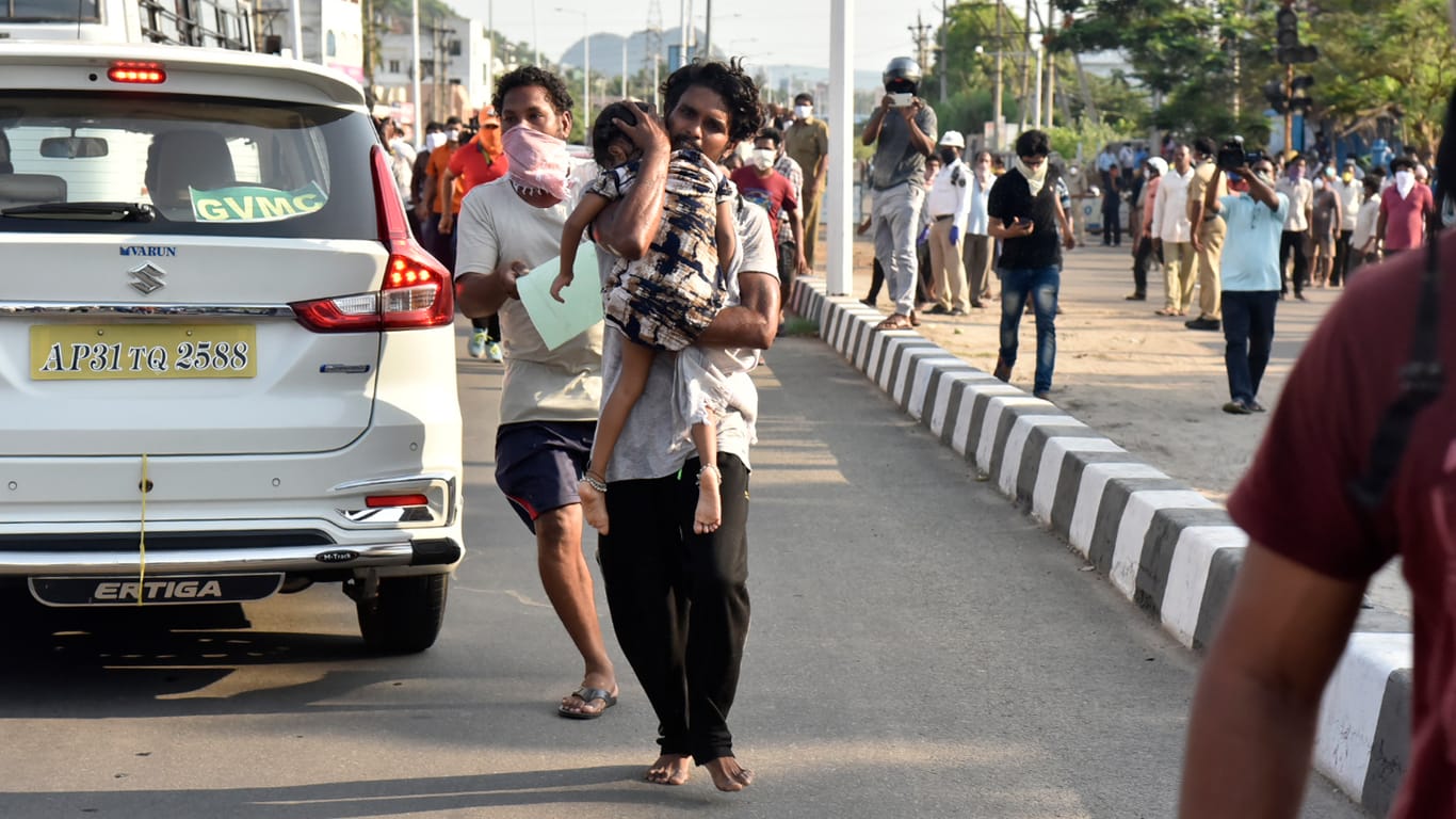 Vishakhapatnam in Indien: Ein Mann trägt ein Kind auf einer Straße, weitere Männer folgen, nach einem Gasunglück an einer Chemiefabrik.