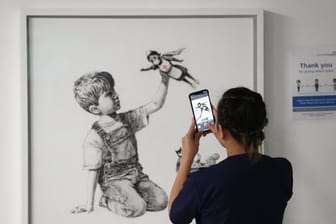 Eine medizinische Mitarbeiterin fotografiert das Banksy-Kunstwerk mit dem Titel "Game Changer".