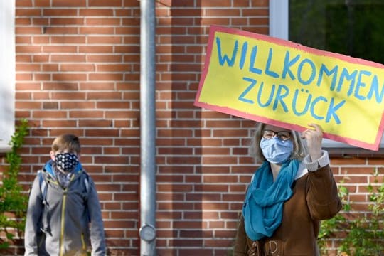 Eine Lehrerin in Schleswig-Holstein begrüßt ihre Schüler mit einem "Willkommen zurück"-Schild.
