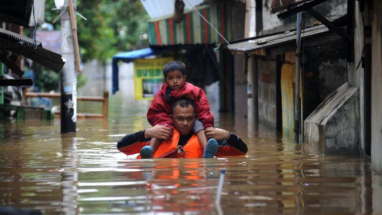 Ein Vater trägt sein Kind auf den Schultern durch die überfluteten Straßen von Jakarta: Schon jetzt kämpfen zahlreiche Länder mit den Folgen des steigenden Meeresspiegels. (Archivbild)