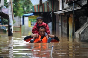 Ein Vater trägt sein Kind auf den Schultern durch die überfluteten Straßen von Jakarta: Schon jetzt kämpfen zahlreiche Länder mit den Folgen des steigenden Meeresspiegels. (Archivbild)