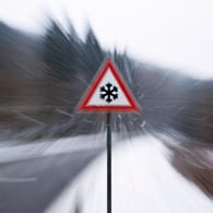 Verkehrsschild mit Eiswarnung bei Schneefall (Symbolbild): Ab kommender Woche kühlt sich das Wetter in Deutschland erheblich ab.