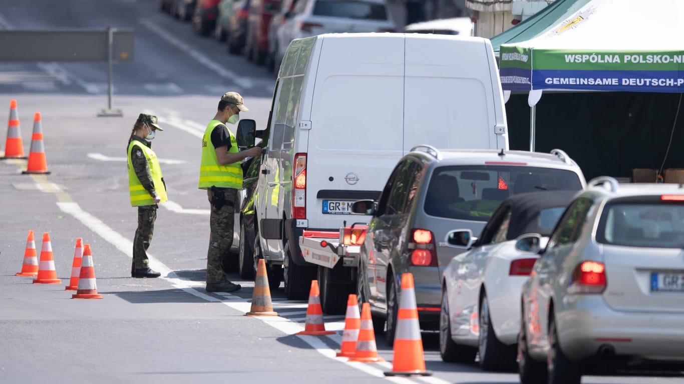 Görlitz: Polnische Grenzpolizisten stehen mit Mundschutz auf der Brücke der Freundschaft an der polnische Grenze vor Zgorzelec und kontrollieren die Personalien der Autofahrer, die auf die polnische Seite fahren wollen.