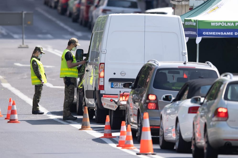 Görlitz: Polnische Grenzpolizisten stehen mit Mundschutz auf der Brücke der Freundschaft an der polnische Grenze vor Zgorzelec und kontrollieren die Personalien der Autofahrer, die auf die polnische Seite fahren wollen.