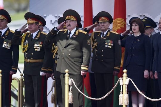 Der weißrussische Präsident Alexander Lukaschenko (M) salutiert, während er die Militärparade in Minsk verfolgt.