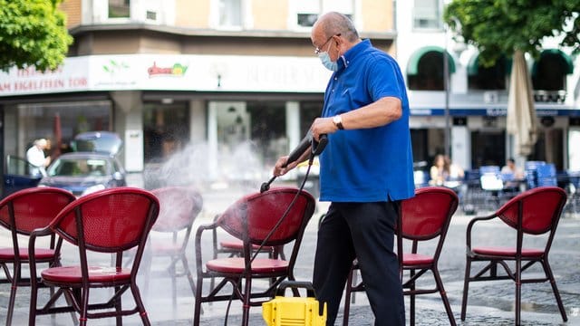 Mit einem Hochdruckreiniger säubert Adriano Maccagnan die Stühle seiner Eisdiele: Nordrhein-Westfälische Gastronomiebetriebe sind nun wieder geöffnet. Mit einem Hochdruckreiniger säubert Adriano Maccagnan die Stühle seiner Eisdiele: Nordrhein-Westfälische Gastronomiebetriebe sind nun wieder geöffnet.